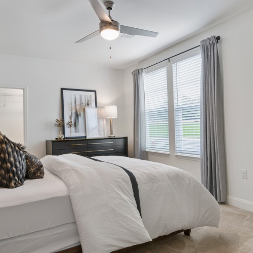 Bright and Airy Bedroom with Ceiling Fan at Aldon at Powell & Broad Bright and spacious bedroom at Aldon at Powell & Broad, showcasing a ceiling fan and large windows that let in natural light in Fuquay-Varina, NC.