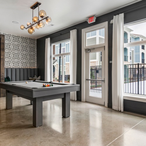 Fun and Relaxation: Game Room with Billiards and Pool View at Aldon at Powell & Broad Game room in the clubhouse at Aldon at Powell & Broad, showcasing a billiards table and TV with a view of the pool in Fuquay-Varina, NC.