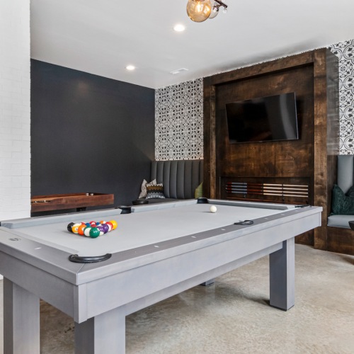 Entertainment Hub: Billiards and Shuffleboard in the Game Room at Aldon at Powell & Broad Game room in the clubhouse at Aldon at Powell & Broad, showcasing billiards, shuffleboard, and multiple TVs for entertainment in Fuquay-Varina, NC.
